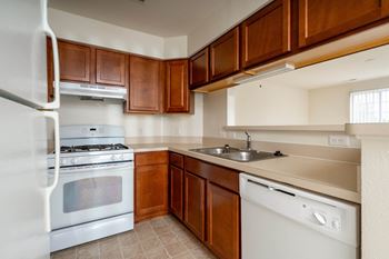 a kitchen with white appliances and wooden cabinetsat The Harbours Apartments, Clinton Twp, MI, 48038